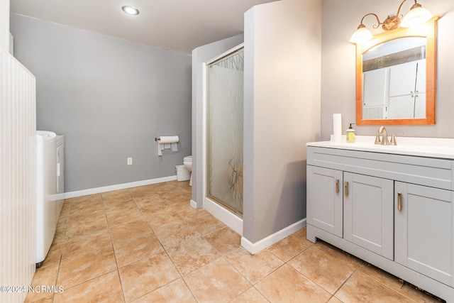 bathroom with tile patterned flooring, an enclosed shower, toilet, washer and clothes dryer, and vanity