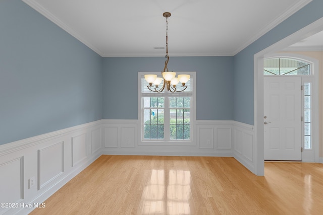 2788 Creek Bridge Ct, Southport, NC 28461 - unfurnished dining area featuring a chandelier, plenty of natural light, light wood-type flooring, wainscoting, and crown molding