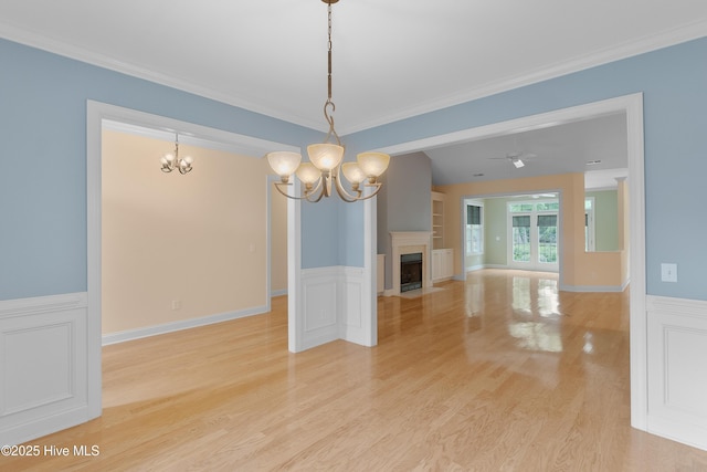 2788 Creek Bridge Ct, Southport, NC 28461 - unfurnished living room with a chandelier, wainscoting, ornamental molding, light wood-style flooring, and built in shelves