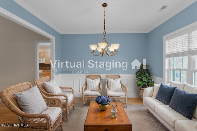 2788 Creek Bridge Ct, Southport, NC 28461 - living room featuring a chandelier, crown molding, a wainscoted wall, and wood finished floors