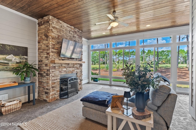 sunroom / solarium featuring a wood stove, ceiling fan, and wooden ceiling