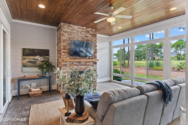 sunroom / solarium with a fireplace, wooden ceiling, ceiling fan, and a healthy amount of sunlight