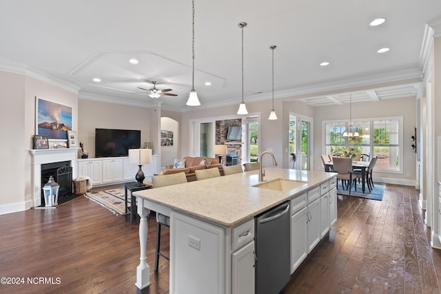 kitchen featuring ceiling fan with notable chandelier, a center island with sink, white cabinets, dark hardwood / wood-style floors, and a stone fireplace