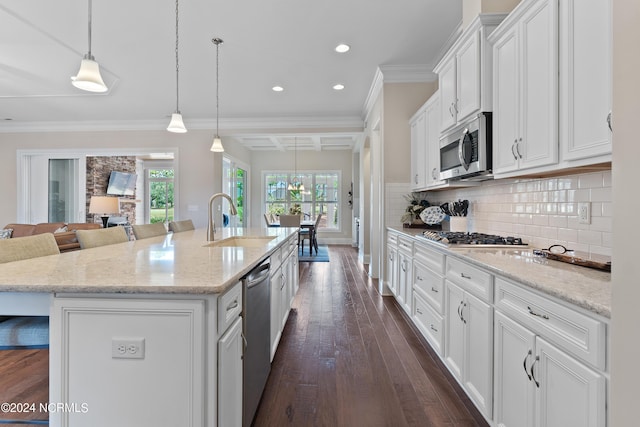 kitchen featuring pendant lighting, a center island with sink, a kitchen breakfast bar, white cabinets, and stainless steel appliances