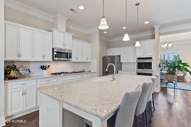 kitchen with white cabinets, stainless steel appliances, dark hardwood / wood-style floors, and a center island with sink