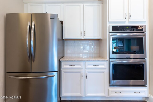 kitchen featuring light stone countertops, decorative backsplash, white cabinets, and stainless steel appliances