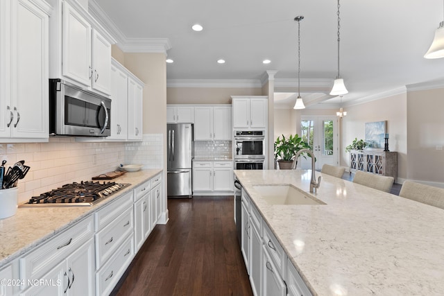 kitchen featuring a kitchen breakfast bar, stainless steel appliances, sink, decorative light fixtures, and white cabinetry