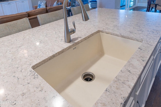 room details with white cabinets, light stone counters, and sink