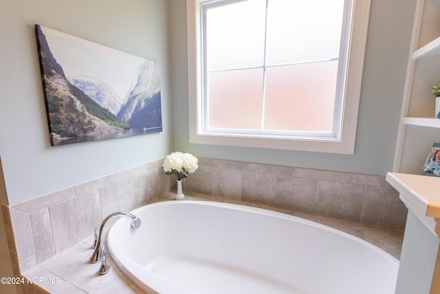 bathroom with built in shelves and tiled bath