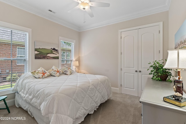 carpeted bedroom with ceiling fan, crown molding, and a closet