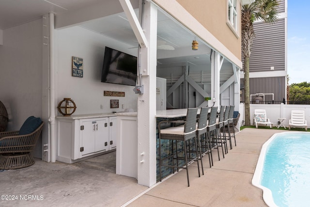 view of patio featuring an outdoor bar and a fenced in pool