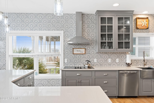 kitchen featuring wall chimney exhaust hood, black electric stovetop, stainless steel dishwasher, and a healthy amount of sunlight