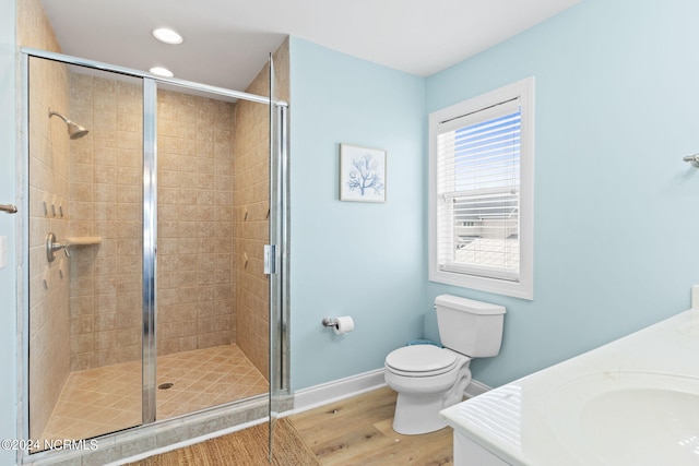 bathroom with hardwood / wood-style flooring, a shower with door, toilet, and vanity