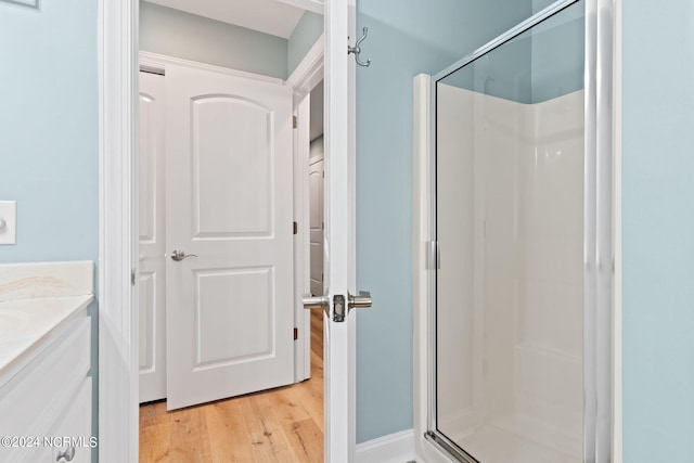 bathroom featuring a shower with door, vanity, and wood-type flooring