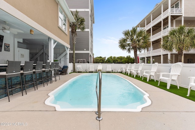 view of swimming pool with a patio, ceiling fan, and exterior bar