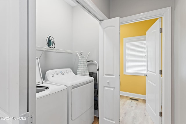 laundry room with washing machine and dryer and light hardwood / wood-style flooring