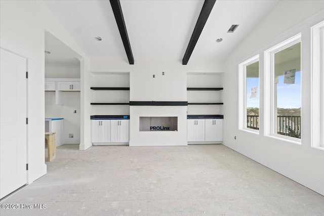 unfurnished living room with beam ceiling and built in shelves