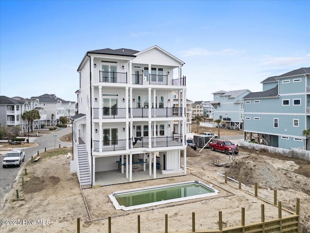 back of property with a balcony, a hot tub, and a patio area