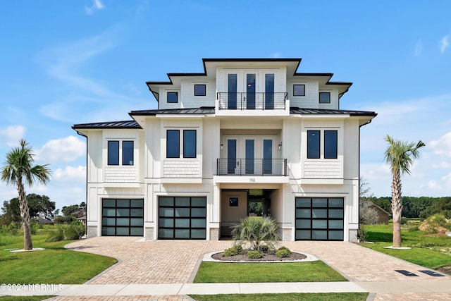 view of front of property featuring a balcony, a standing seam roof, an attached garage, and french doors