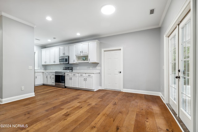 kitchen with ornamental molding, stainless steel appliances, white cabinets, and light wood-type flooring