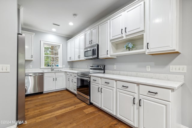 kitchen featuring white cabinets, appliances with stainless steel finishes, crown molding, and dark hardwood / wood-style flooring