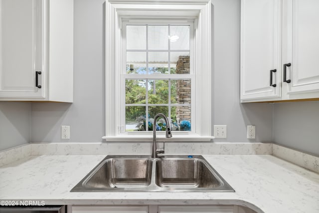 kitchen with sink, light stone counters, and white cabinets