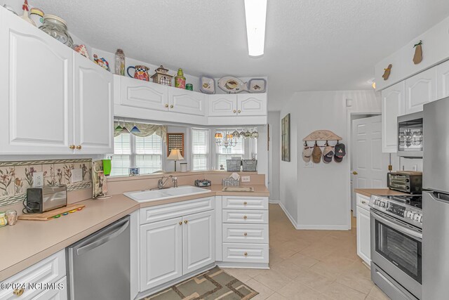 kitchen featuring stainless steel appliances, white cabinetry, sink, light tile patterned floors, and kitchen peninsula