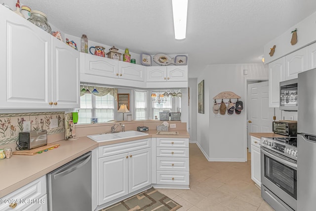 kitchen with white cabinets, appliances with stainless steel finishes, light countertops, a textured ceiling, and a sink