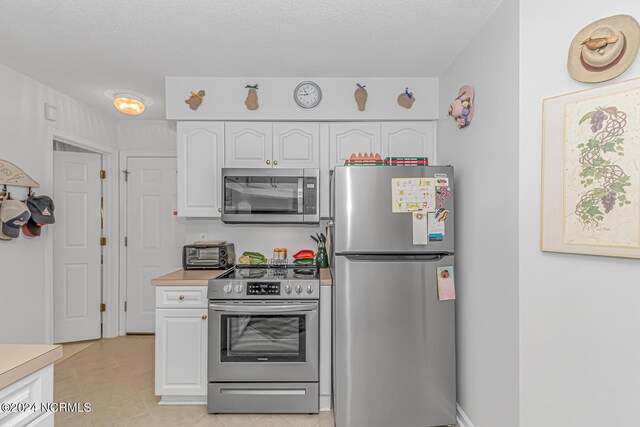 kitchen featuring light tile patterned floors, stainless steel appliances, and white cabinets