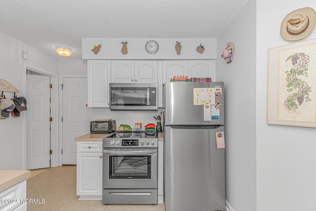 kitchen featuring a toaster, light countertops, appliances with stainless steel finishes, white cabinetry, and light tile patterned flooring