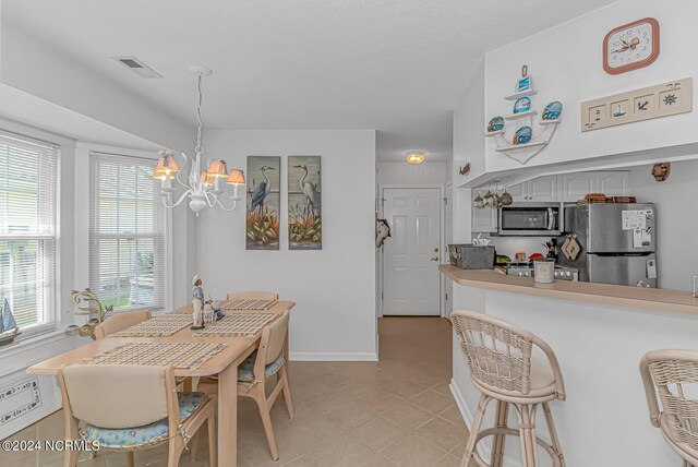 tiled dining area featuring an inviting chandelier and a healthy amount of sunlight