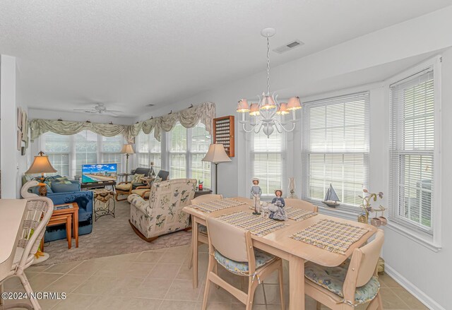 tiled dining area with ceiling fan with notable chandelier and a wealth of natural light