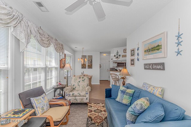 living room with ceiling fan with notable chandelier