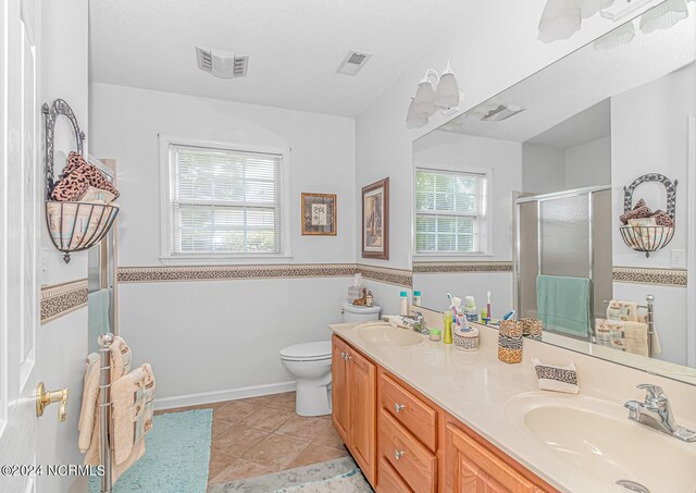 bathroom with tile patterned flooring, a shower with door, vanity, and toilet