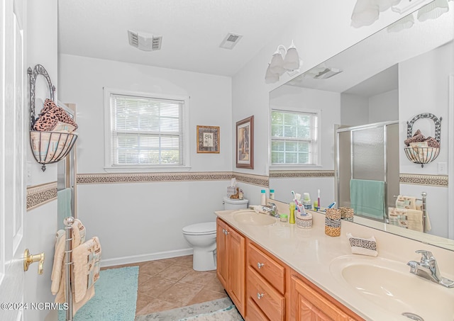 bathroom featuring toilet, a stall shower, a sink, and visible vents