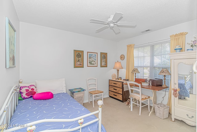 carpeted bedroom featuring ceiling fan and a textured ceiling