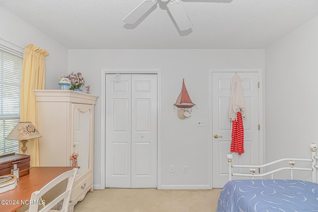 bedroom with light carpet, baseboards, ceiling fan, a textured ceiling, and a closet