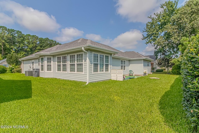 back of property featuring a lawn and central air condition unit