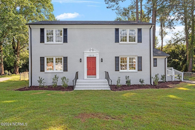 colonial inspired home with entry steps, brick siding, and a front yard