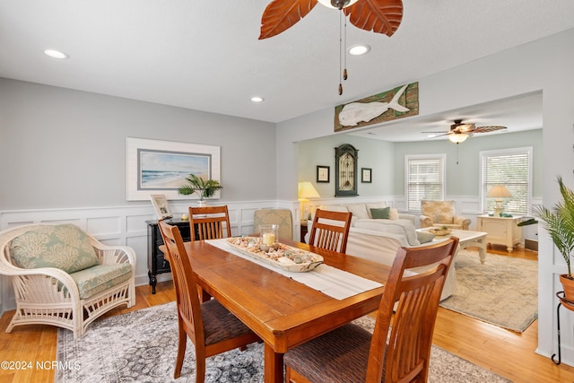 dining space with a wainscoted wall, recessed lighting, light wood-style floors, a ceiling fan, and a textured ceiling