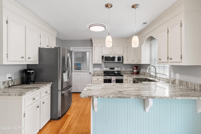 kitchen with a peninsula, white cabinetry, stainless steel appliances, and a sink