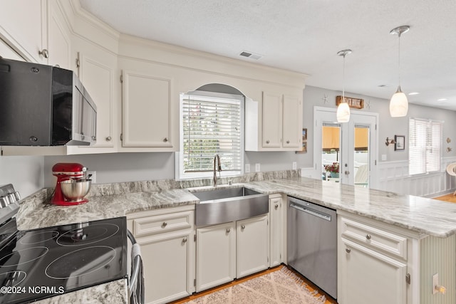 142 Carolina Ave, Holden Beach, NC 28462 - kitchen with stainless steel appliances, a sink, a peninsula, pendant lighting, and a textured ceiling