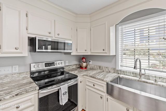 kitchen with stainless steel appliances, white cabinetry, a sink, and light stone countertops