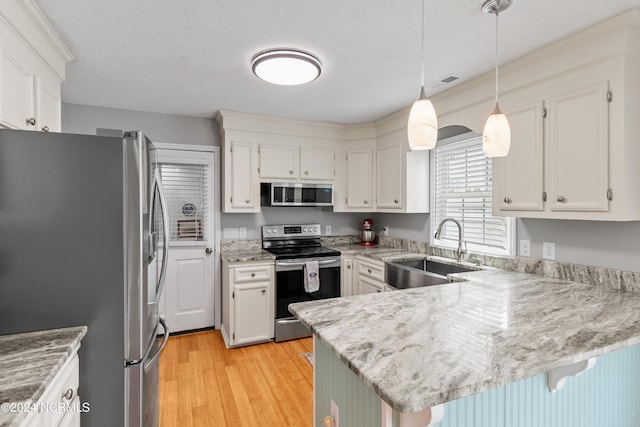 142 Carolina Ave, Holden Beach, NC 28462 - kitchen featuring appliances with stainless steel finishes, a sink, a peninsula, light wood finished floors, and a kitchen bar