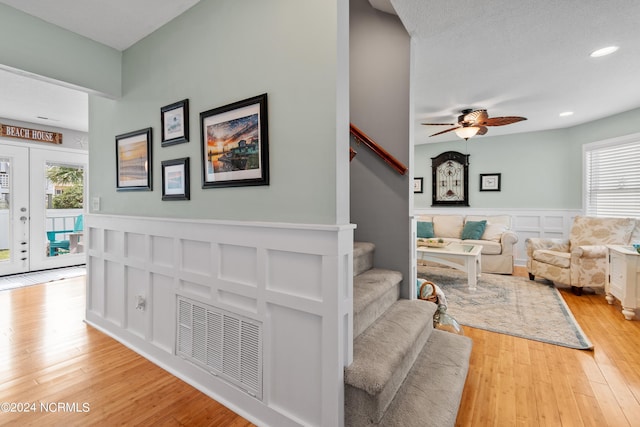 142 Carolina Ave, Holden Beach, NC 28462 - living area with stairway, light wood-type flooring, wainscoting, a ceiling fan, and plenty of natural light