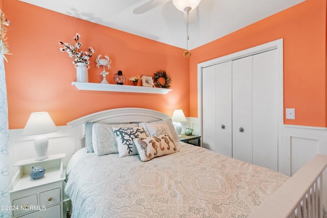 bedroom with ceiling fan, a decorative wall, a closet, and wainscoting