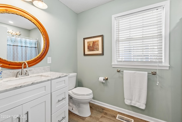 full bath featuring toilet, wood finished floors, vanity, visible vents, and baseboards