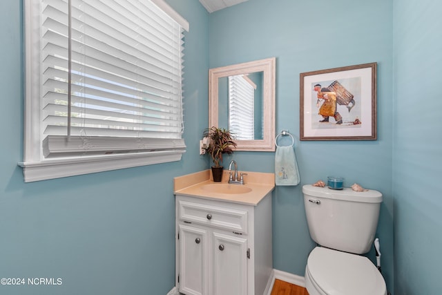 half bath with vanity, toilet, and baseboards