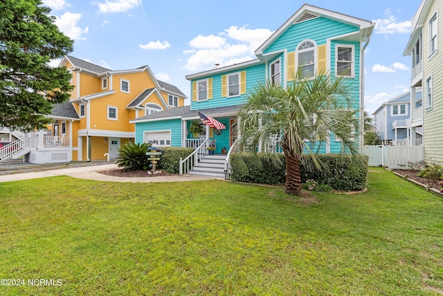 raised beach house with a garage, fence, driveway, and a front lawn