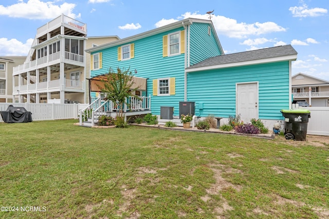 back of property with a lawn and fence